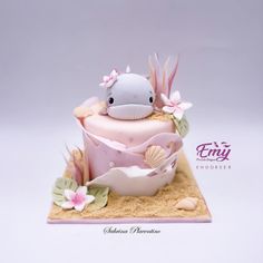 a pink cake decorated with an animal and seashells