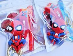 two spider - man keychains in plastic bags on a white surface with blue and red accents