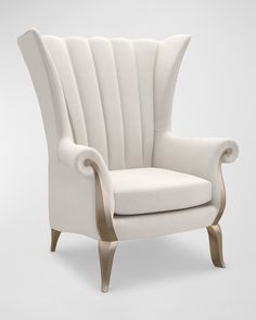 a white chair with gold trim on the armrests and back, sitting in front of a gray background