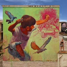 a man is standing in front of a large mural on the side of a building