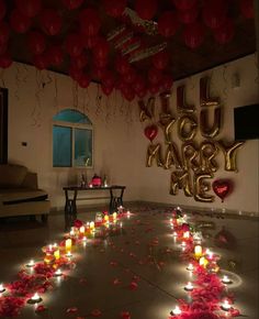 a room filled with lots of candles and balloons in the shape of hearts on the floor