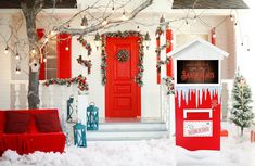 a red mailbox sitting in front of a white house with snow on the ground