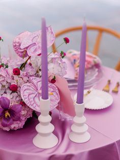 a table topped with purple flowers and candles