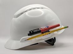 a white hard hat with pencils and markers on it