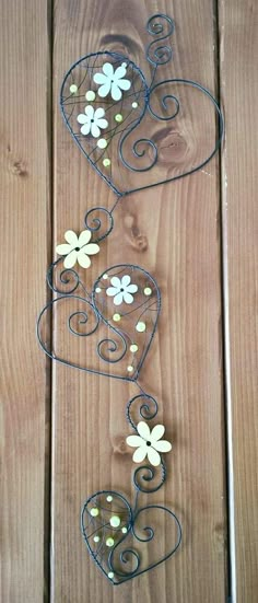 a metal heart with flowers on it sitting on top of a wooden table next to a fence