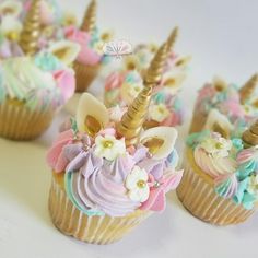 small cupcakes decorated with pastel frosting and unicorn - like decorations are on display