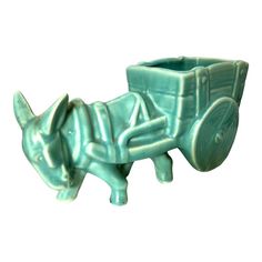 a small green planter shaped like a horse and carriage with a dog on it