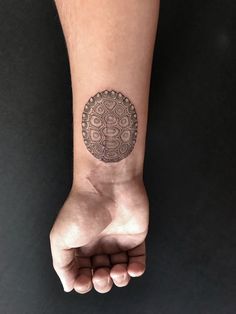 a person's arm with a tattoo on it and a circular design on the wrist