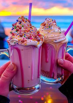 two people are holding up drinks with sprinkles on the top and bottom