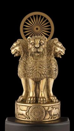 a golden lion statue sitting on top of a black surface with the sun in it's center