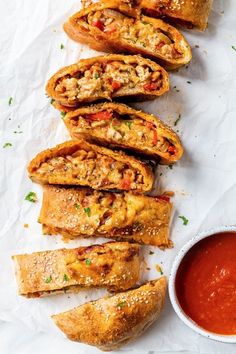 several pastries are lined up next to a bowl of sauce