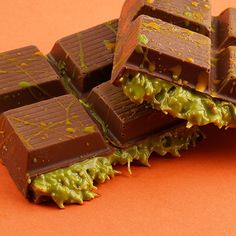 pieces of chocolate with green sprinkles on an orange surface, one half eaten