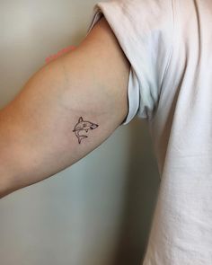 a small tattoo on the arm of a man's left arm, which has a line drawing of a shark