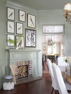 a living room with pictures on the wall and a fireplace in the center, surrounded by white chairs