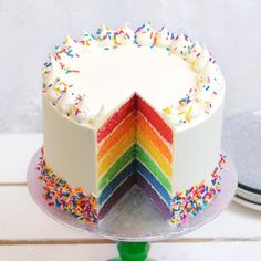 a rainbow cake with white frosting and sprinkles