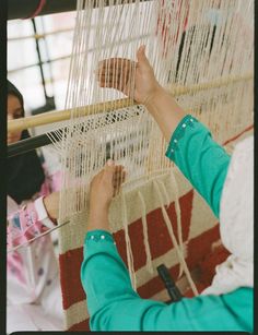 a woman is weaving on a large loom