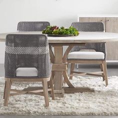 a dining room table with two chairs and a bowl of vegetables on top of it