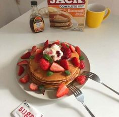 a stack of pancakes topped with strawberries and whipped cream