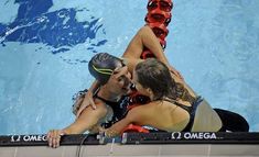 a man and woman are in the water next to a swimming pool with their arms around each other