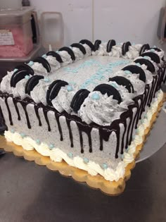 a cake with white frosting and chocolate drizzles on the top is sitting on a table