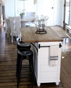 a kitchen island with stools on top of it in front of a dining room table