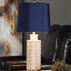 a table lamp sitting on top of a wooden table next to a black leather chair