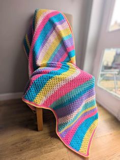 a colorful crocheted blanket sitting on top of a wooden chair