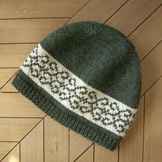 a green and white knitted hat laying on top of a wooden floor