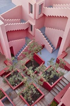 an aerial view of a pink building with trees in the courtyard