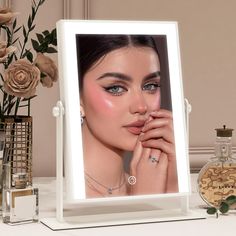 a woman's face is reflected in a mirror next to flowers and perfume bottles