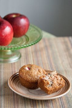 two muffins on a plate next to some apples