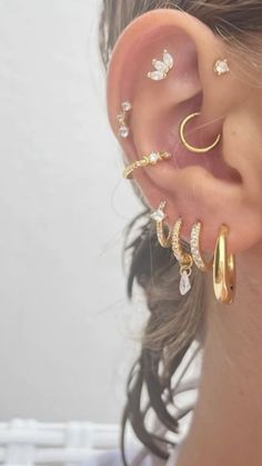 a woman wearing three different types of ear piercings on her left side of the ear