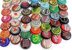 a pile of beer bottle caps sitting next to each other on top of a white surface