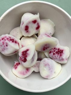 a white bowl filled with cut up pieces of food on top of a green table