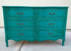 an old dresser painted in teal green with gold hardware