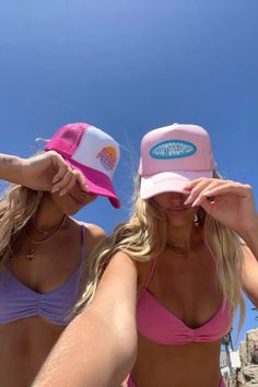 two women in bikinis and hats on the beach