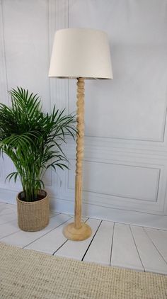 a floor lamp next to a potted plant in a room with white paneling