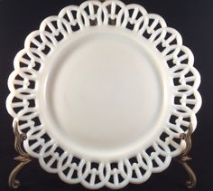 an ornate white plate with gold trim on a black tableclothed surface, set against a black background