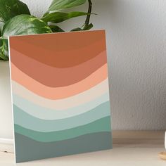 a card with an orange, blue and green ombreache on it next to a potted plant