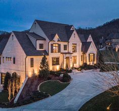 a large white house with lots of windows and lights on it's front yard