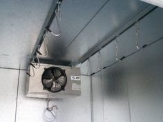 an air conditioner mounted to the side of a wall with wires hanging from it