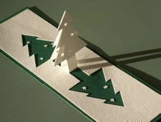 an origami christmas tree on a green and white tablecloth with the shadow of a person