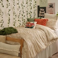 a bed with pillows and blankets on top of it next to a plant covered wall