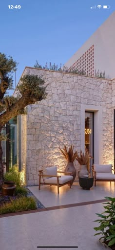 an outdoor living area is lit up with lights and potted plants on the patio