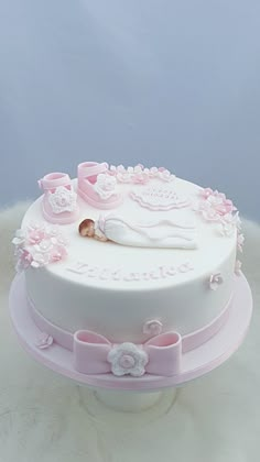 a baby's first birthday cake with pink decorations and booties on the top