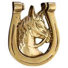 a gold horse head mounted on the side of a metal door knocker with a white background