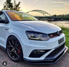 a white car parked on the side of a road next to a body of water