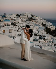 a bride and groom embracing on the roof of a building in oia, greece