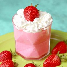 some strawberries are sitting on a plate next to a small cup with whipped cream