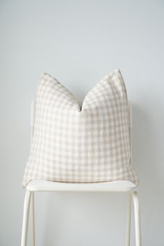 a white chair with a checkered pillow on it's back and the seat up